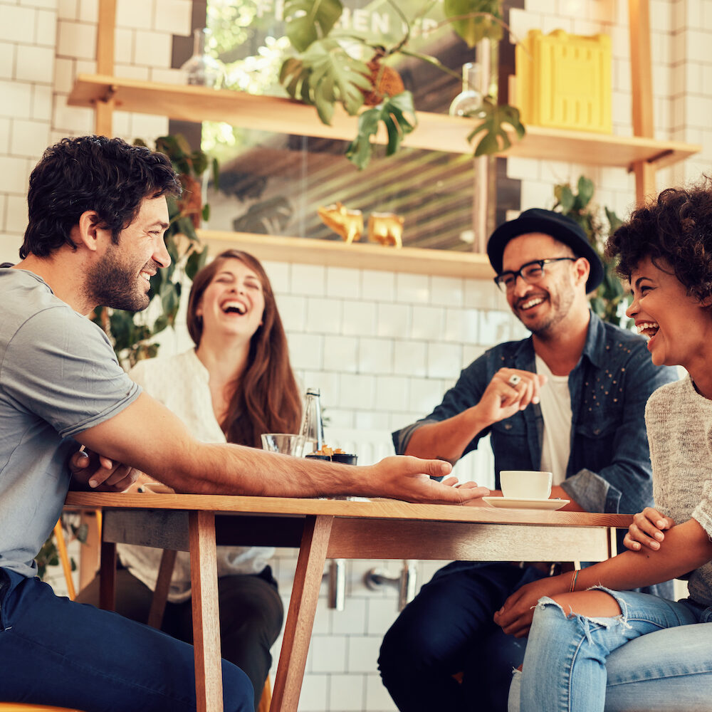 Young friends having a great time in restaurant. Group of young people sitting in a coffee shop and smiling.